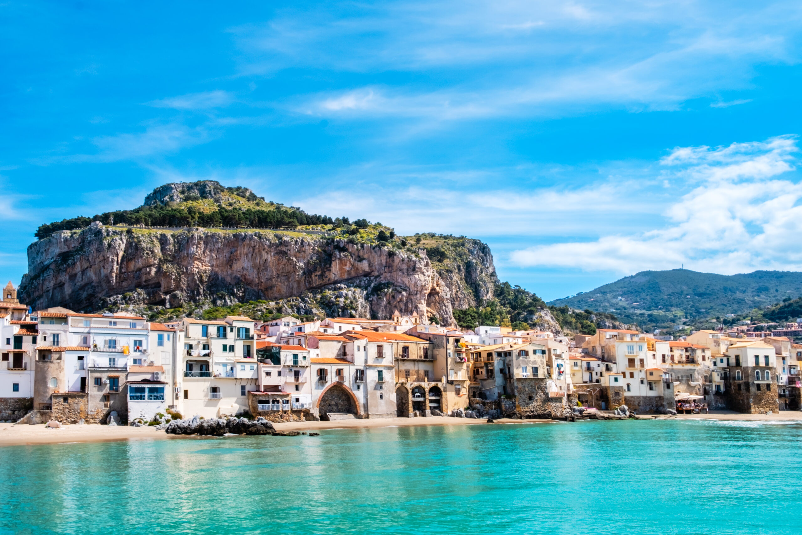 Cefalu, medieval town on Sicily island, Italy. Seashore village with beach and clear turquoise water of Tyrrhenian sea, surrounded with mountains. Popular tourist attraction in Province of Palermo